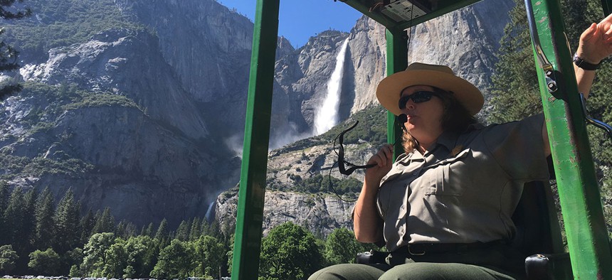 A guide at Yosemite National Park, Calif., talks to tourists with Yosemite Falls behind her. 
