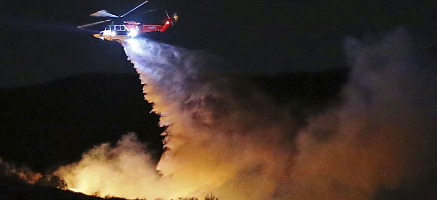 A helicopter makes a water drop on a brush fire that broke out near Los Angeles on Wednesday evening, Feb. 21, 2018.