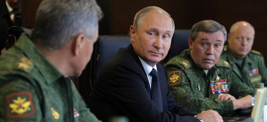 Russian President Vladimir Putin, center, speaks to Defence Minister Sergei Shoigu, left, as Chief of the General Staff of the Russian Armed Forces Valery Gerasimov, second right, looks on.