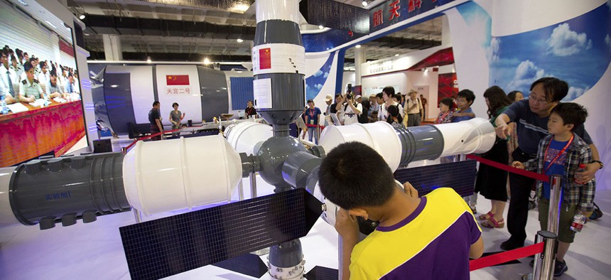 Visitors look at a model of China's Tiangong-1 space station at the China Beijing International High-Tech Expo in Beijing, Saturday, June 10, 2017. 