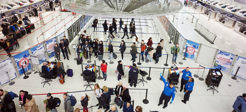 Passengers stand in line as they wait to pass through a TSA security checkpoint at JFK International Airport in New York. 