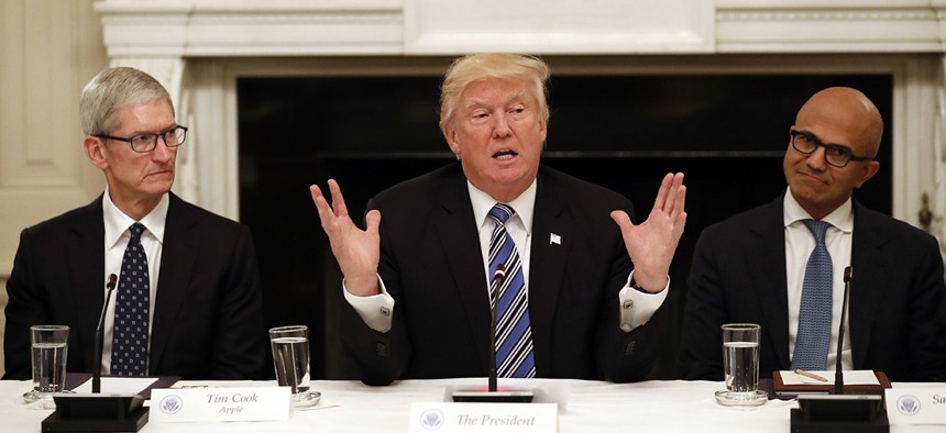 President Donald Trump, center, speaks as he is seated between Tim Cook, Chief Executive Officer of Apple, left, and Satya Nadella, Chief Executive Officer of Microsoft, right, during an American Technology Council roundtable.
