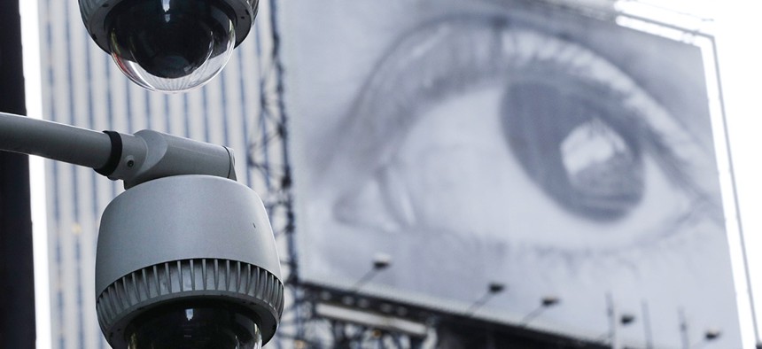 Security cameras are mounted on the side of a building overlooking an intersection in midtown Manhattan.