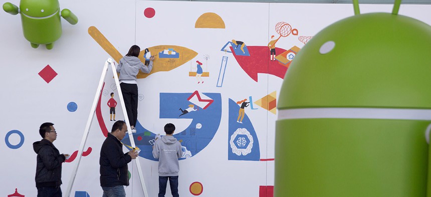 Attendees at the Google Developer Day walks past a mural being painted in Beijing, China, Thursday, Dec. 8, 2016. 