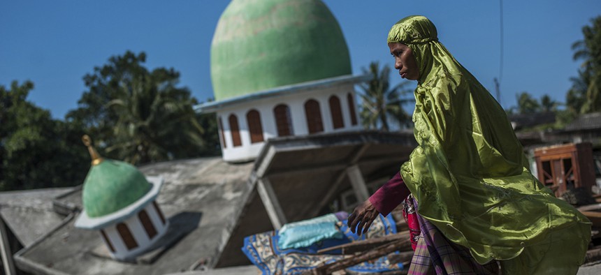 A woman walks past a mosque collapsed during Sunday's earthquake in Gangga, Lombok Island, Indonesia. 