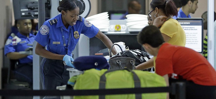 A Transportation Security Administration officer checks travelers luggage to be screened by an x-ray machine at a checkpoint at Fort Lauderdale-Hollywood International Airport.