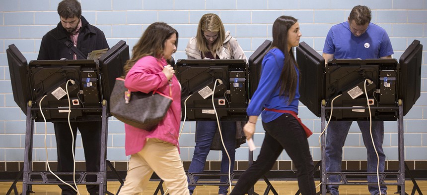 A poll worker leads a voter to an electronic voting machine at the Schiller Recreation Center polling station on election day in Columbus, Ohio.