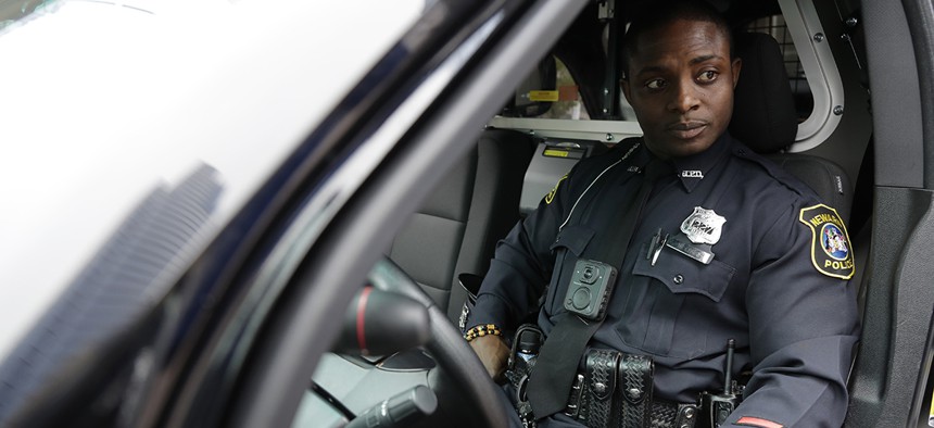 Newark Police officer William Essien sits in a police vehicle while wearing a body camera.