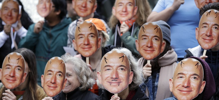 Demonstrators hold images of Amazon CEO Jeff Bezos near their faces during a Halloween-themed protest at Amazon headquarters over the company's facial recognition system.