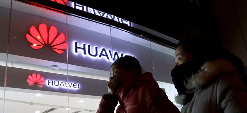 Women walk past a Huawei retail shop in Beijing Thursday, Dec. 6, 2018. 