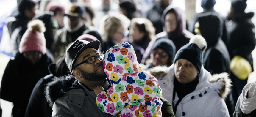 A furloughed federal worker holds his daughter as they wait in line with others who are affected by the partial government shutdown for Philabundance volunteers to distribute food under Interstate 95 in Philadelphia Jan. 23.