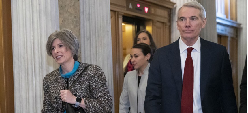 Sens. Joni Ernst, left, and Rob Portman head to the Senate floor prior to a vote on ending the partial government shutdown Jan. 24.