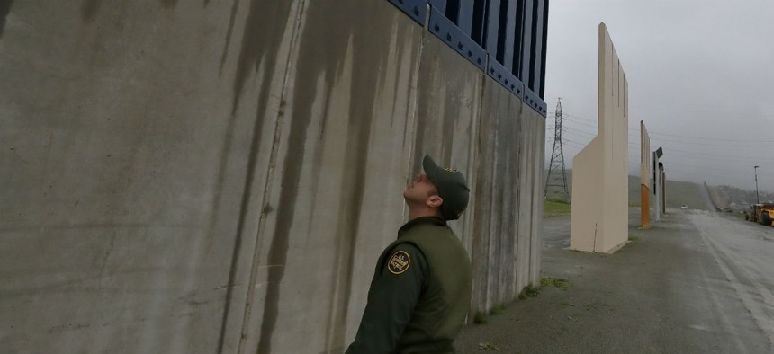 A Border Patrol agent walks towards prototypes for a border wall Feb. 5 in San Diego. 