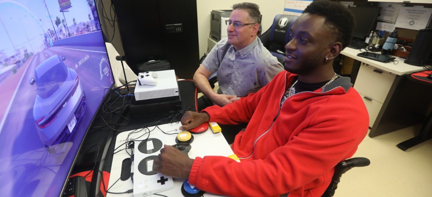 Mike Monthervil, U.S. Army veteran (front), and Jamie Kaplan, recreation therapist at James A. Haley Veterans’ Hospital in Tampa, Fla., play a video game using an Xbox Adaptive Controller.