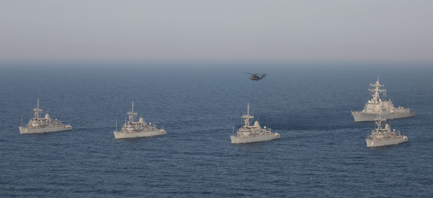 A formation of Avenger-class mine countermeasure ships USS Devastator, USS Gladiator, USS Sentry, USS Dextrous, the Arleigh Burke-class guided missile destroyer USS Mason and an MH-53E Sea Dragon helicopter during a maneuver in the Arabian Gulf July 6.