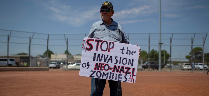 A man holds a sign to protest the visit of President Donald Trump to the border city after the Aug. 3 mass shooting in El Paso, Texas, Aug. 7.