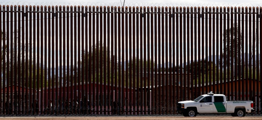 A Customs and Border Protection vehicle sits near the wall along a new section of the border wall with Mexico in Calexico, Calif.