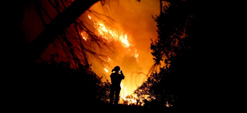 A firefighter takes a cell phone picture during a wildfire Saturday, Dec. 16, 2017, in Montecito, Calif.