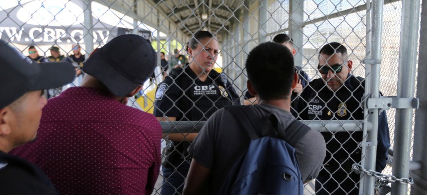 Migrants ask Customs and Border Protection officers when will the border re-open, after camping out on the Gateway International Bridge that connects downtown Matamoros, Mexico with Brownsville Oct. 10.