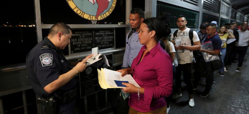 A Customs and Border Protection officer checks the documents of migrants who are on their way to apply for asylum in the United States as they depart Nuevo Laredo, Mexico, in September.