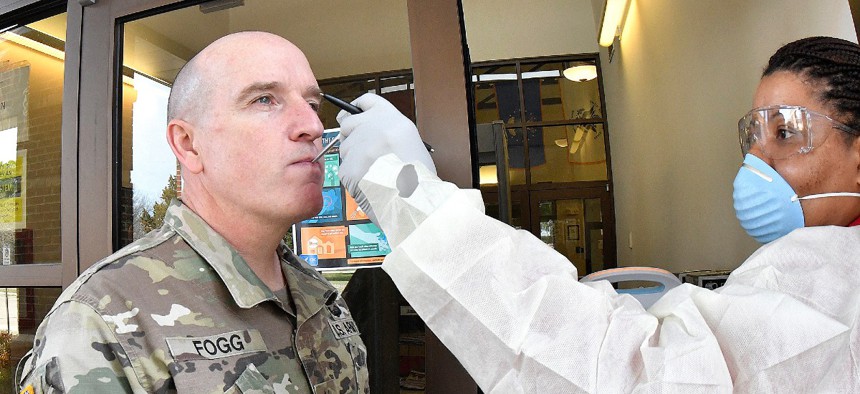 Maj. Gen. Rodney Fogg, Fort Lee commanding general, gets his temperature taken by Lagina Johnson of the Military Entrance Processing Station upon access to the facility March 17.