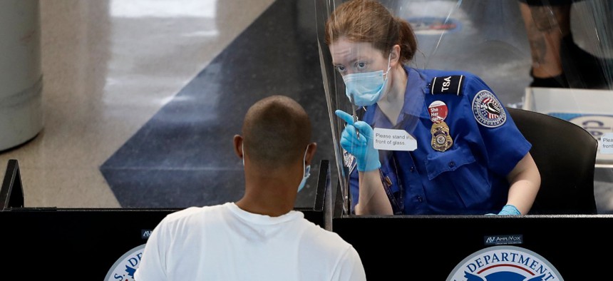 TSA officers wear protective masks at a security screening area at Seattle-Tacoma International Airport in SeaTac, Wash. 