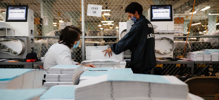Workers use an electronic scanner as they process stacks of ballots at a Board of Elections facility, Wednesday, July 22, 2020, in New York. 