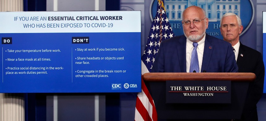 CDC Director Robert Redfield speaks as charts are displayed during a briefing about the coronavirus at a White House briefing April 8 as Vice President Mike Pence listens.