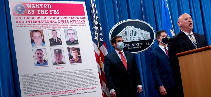 A poster showing six wanted Russian military intelligence officers is displayed as Justice Department officials brief on the press on new indictments Oct. 19.