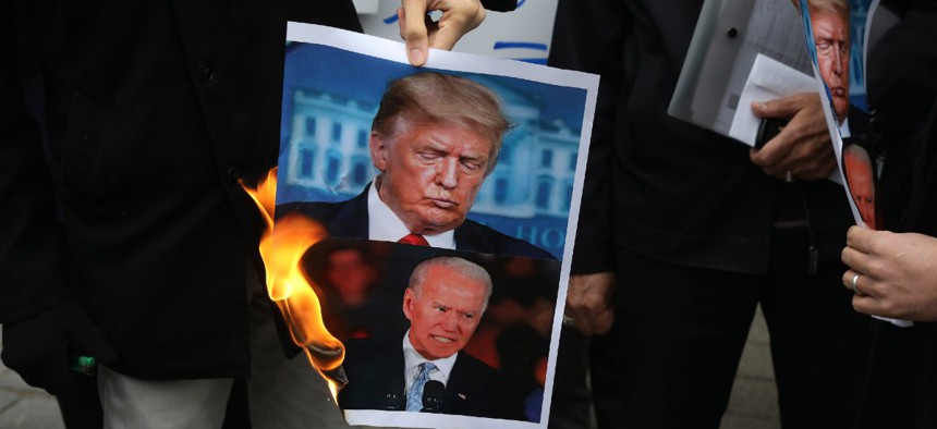 Protesters burn pictures of the U.S. President Donald Trump, top, and the President-elect Joe Biden in a gathering in front of Iranian Foreign Ministry on Nov. 28, a day after the killing of Iranian scientist Mohsen Fakhrizadeh.