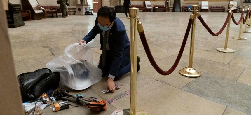 Rep. Andy Kim, D-N.J., cleans up debris and personal belongings strewn across the floor of the Rotunda in the early morning hours of Thursday, Jan. 7, 2021, after protesters stormed the Capitol.