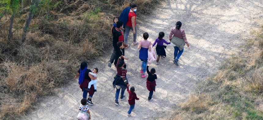 Migrants walk on a dirt road after crossing the U.S.-Mexico border on March 23 in Mission, Texas.