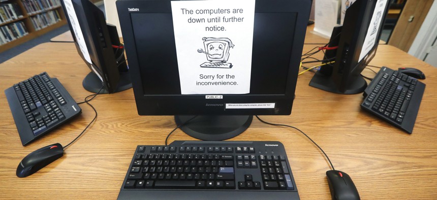In this Aug. 22, 2019 photo, signs on a bank of computers tell visitors that the machines are not working at the public library in Wilmer, Texas. 