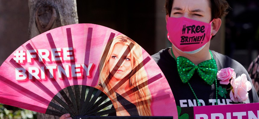 Britney Spears supporter Dustin Strand of Phoenix holds a hand fan outside a court hearing concerning the pop singer's conservatorship at the Stanley Mosk Courthouse, Wednesday, March 17, 2021, in Los Angeles.