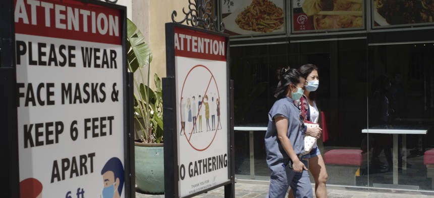 In this June 11, 2021, file photo, customers wear face masks in an outdoor mall with closed business amid the COVID-19 pandemic in Los Angeles. The latest alarming coronavirus variant, the delta variant, is exploiting low global vaccination rates and a rush to ease pandemic restrictions, adding new urgency to the drive to get more shots in arms and slow its supercharged spread.