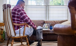 A Hispanic American veteran double amputee on a telemedicine call with his doctors at home.