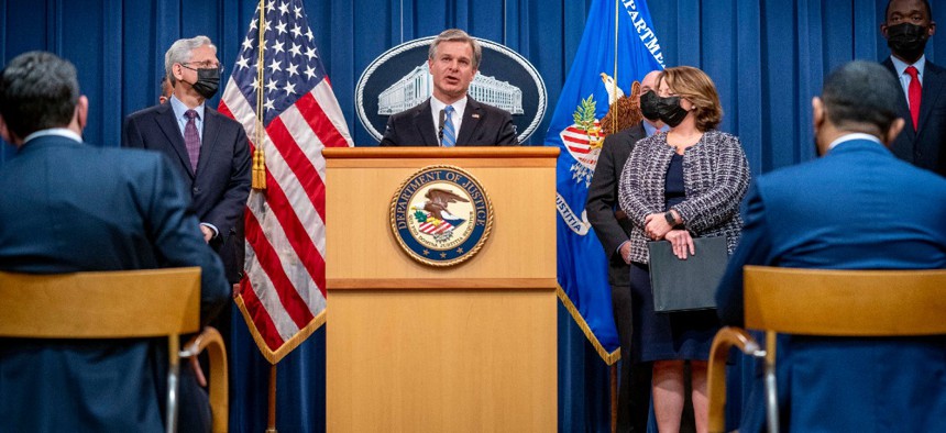 FBI Director Christopher Wray, center, Attorney General Merrick Garland, left,  and Deputy Attorney General Lisa Monaco, right, announce charges Monday against Ukrainian Yaroslav Vasinskyi and Russian Yevgeniy Polyanin, alleging them to be part of the REvil ransomware gang.