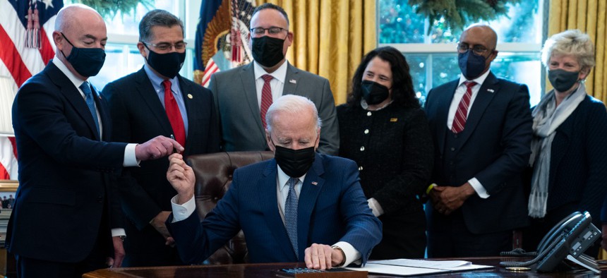 President Biden hands a pen to Homeland Security Secretary Alejandro Mayorkas as he signs an executive order to improve government services in the Oval Office of the White House on Monday. 