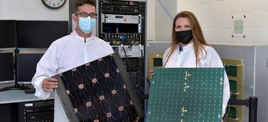 Project Managers James Winter (Air Force Research Laboratory) and Tara Theret (Northrop Grumman) hold models of the photovoltaic and the radio frequency sides of the sandwich tile, while at the Linthicum, Maryland facility, to witness the conversion and beaming experiment.