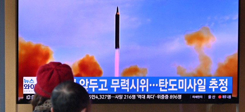 People watch a television screen showing a news broadcast with file footage of a North Korean missile test, at a railway station in Seoul on March 5, 2022, after North Korea fired at least one "unidentified projectile" in the country's ninth suspected weapons test this year according to the South's military. 
