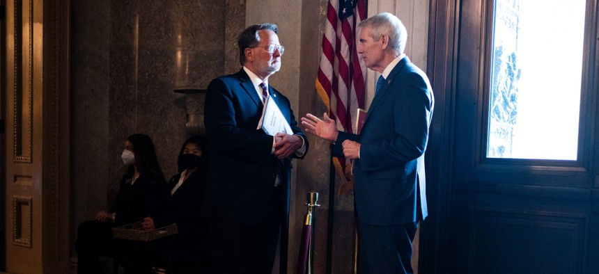 Sens. Gary Peters (left) and Rob Portman confer in the U.S. Capitol Building