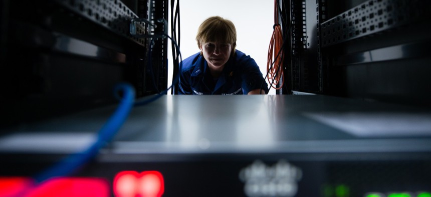 U.S. Coast Guard Chief Warrant Officer DeAnna Melleby, Information Systems Security Officer for the Coast Guard Command, Control, Communication and Information Technology unit at Coast Guard Base Boston, peers through a space in a server April 20, 2017.