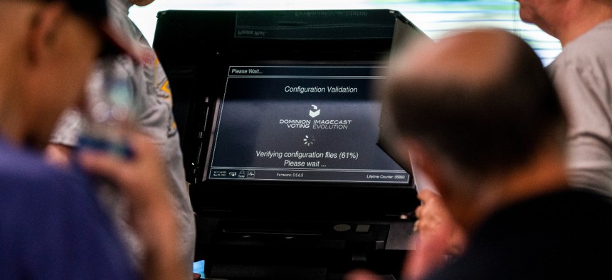 Election judges set up ballot counting machines as public observers look on during a public accuracy test of voting equipment on August 3, 2022 in Burnsville, Minnesota.