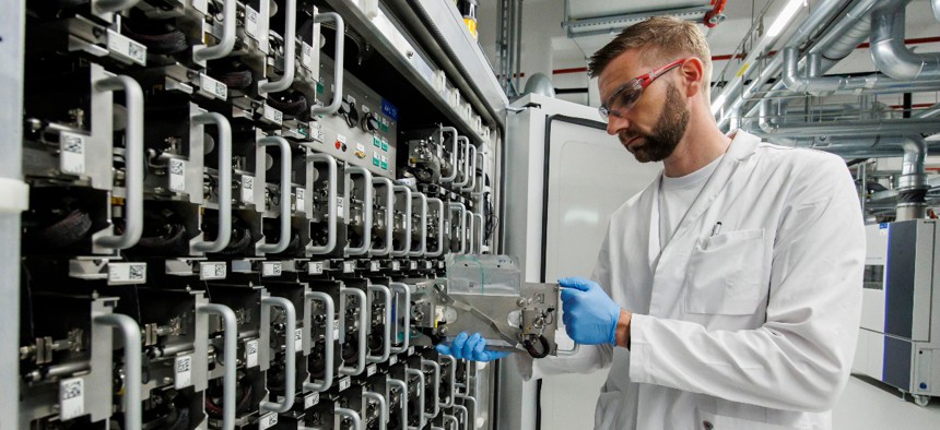  A Volkswagen employee demonstrates how to insert a single cell test pouch in a battery cell test chamber for electric car battery at the pilot project for Volkswagen's own electric car battery production facility on May 18, 2022 in Salzgitter, Germany. 
