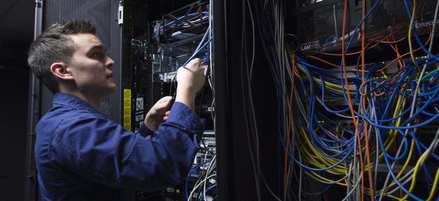 A Coast Guard Information Systems Technician adjusts cables inside a server room at the Telecommunication and Information Systems Command (TISCOM) Jan. 24, 2013.