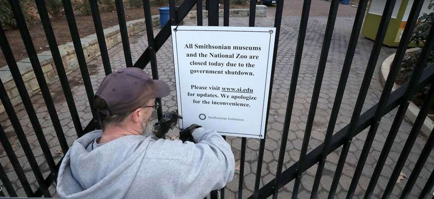 A Smithsonian National Zoo employee removes a sign from the front gate telling visitors that the zoo is closed due to a government shutdown January 28, 2019 in Washington, D.C.