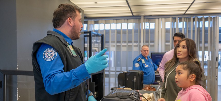 TSA agent Joshua Antelo explains to the Chin family the first step of removing their dog from its carrying case during a demonstration to show the proper way to bring a pet through security at Dulles International Airport.