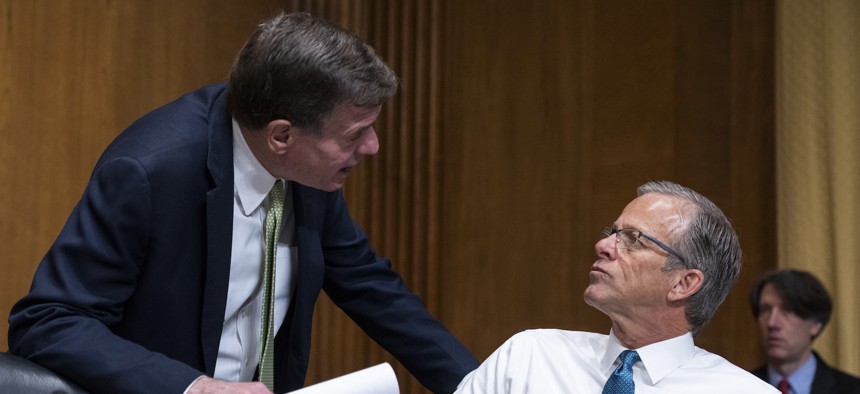 Sens. Mark Warner (L) and John Thune confer at a hearing in February 2023. The Virginia Democrat and the South Dakota Republican are teaming up on legislation to introduce cybersecurity guidelines for the federal government's fleet of drone aircrart.