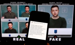 This illustration photo taken on January 30, 2023 shows a phone screen displaying a statement from the head of security policy at META with a fake video (R) of Ukrainian President Volodymyr Zelensky calling on his soldiers to lay down their weapons shown in the background.