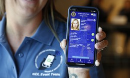A Utah state worker displays a sample mobile drivers license at a 2021 event. Utah is currently one of nine states to offer mDLs. Some in Congress want more information on how digital IDs impact transportation security.